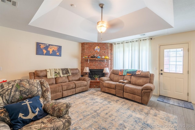 20903 E 35th St S, Broken Arrow, OK 74014 - living area with wood finished floors, a tray ceiling, ceiling fan, and a fireplace