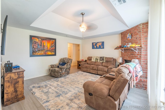 20903 E 35th St S, Broken Arrow, OK 74014 - living area with a raised ceiling, ceiling fan, wood finished floors, a brick fireplace, and baseboards