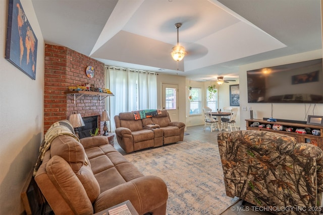 20903 E 35th St S, Broken Arrow, OK 74014 - living room featuring a ceiling fan, a tray ceiling, and a brick fireplace