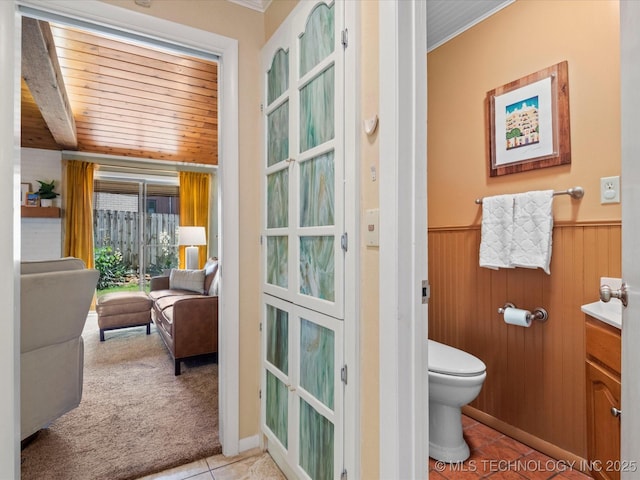 2310 Skyline Dr, Bartlesville, OK 74006 - bathroom with tile patterned flooring, toilet, a wainscoted wall, ornamental molding, and wood ceiling