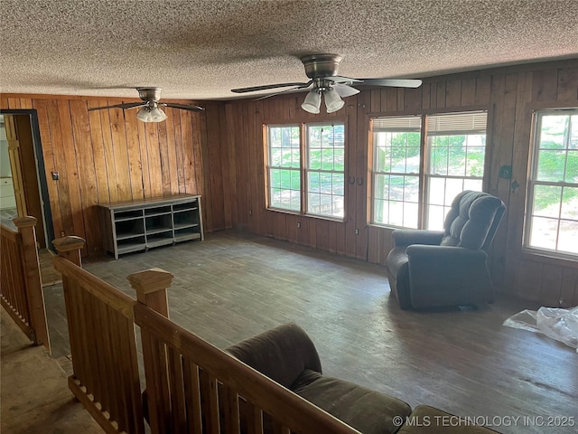 98 Whispering Pines Ln, Stigler, OK 74462 - living room featuring wooden walls, a ceiling fan, wood finished floors, and a textured ceiling