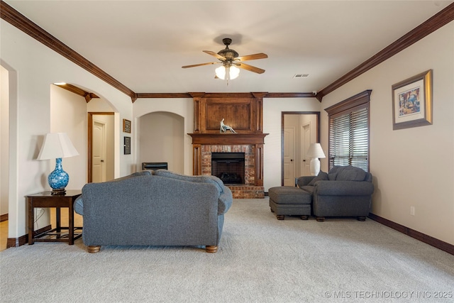 6601 E 85th St, Owasso, OK 74055 - carpeted living room featuring a ceiling fan, ornamental molding, baseboards, arched walkways, and a fireplace