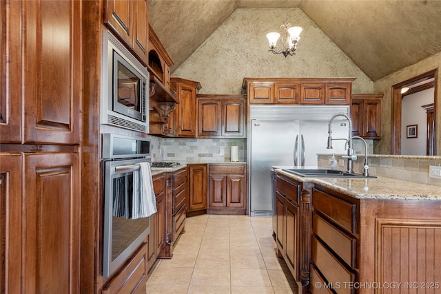 6601 E 85th St, Owasso, OK 74055 - kitchen featuring built in appliances, decorative backsplash, light stone countertops, a chandelier, and brown cabinetry