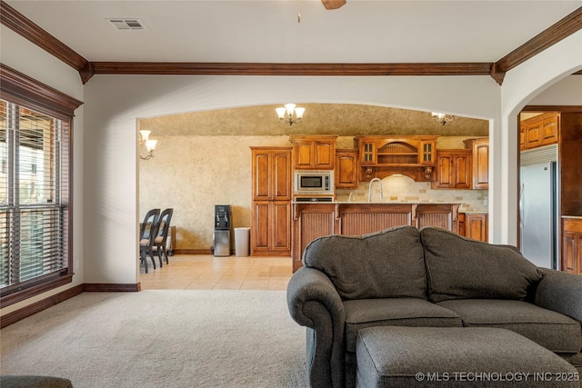 6601 E 85th St, Owasso, OK 74055 - living room featuring ornamental molding, arched walkways, light carpet, baseboards, and light tile patterned flooring