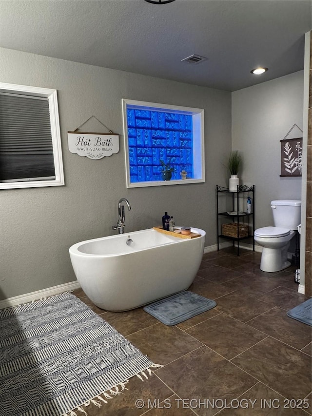 1105 Ono Ct, Mcalester, OK 74501 - bathroom featuring a freestanding bath, toilet, baseboards, tile patterned flooring, and a textured wall