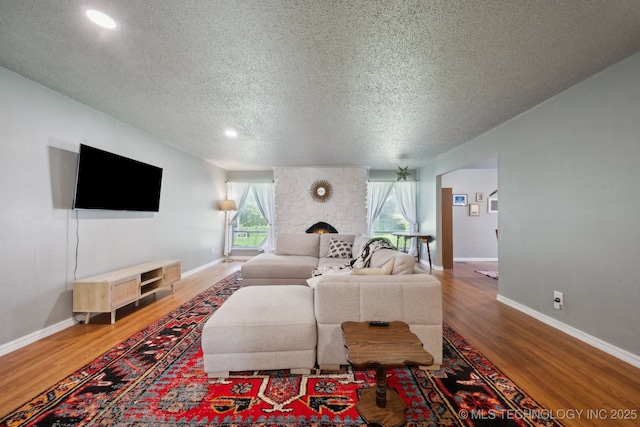 6960 S Oswego Ave, Tulsa, OK 74136 - living area with wood finished floors, a textured ceiling, baseboards, a fireplace, and recessed lighting
