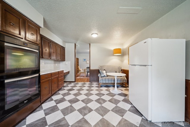 6960 S Oswego Ave, Tulsa, OK 74136 - kitchen with freestanding refrigerator, double oven, light countertops, a textured ceiling, and light flooring