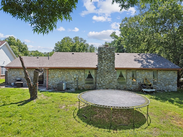 6960 S Oswego Ave, Tulsa, OK 74136 - rear view of house with stone siding, a trampoline, cooling unit, and a yard