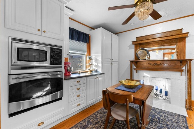722 E 18th St, Ada, OK 74820 - kitchen with appliances with stainless steel finishes, ceiling fan, white cabinets, light wood finished floors, and ornamental molding
