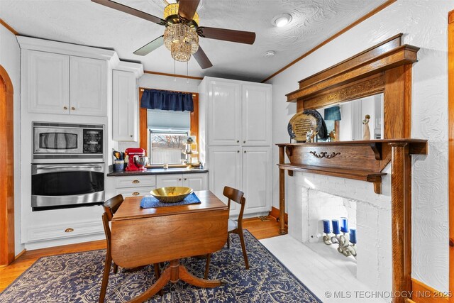 722 E 18th St, Ada, OK 74820 - dining room featuring ceiling fan, light wood-style flooring, a fireplace with flush hearth, and arched walkways