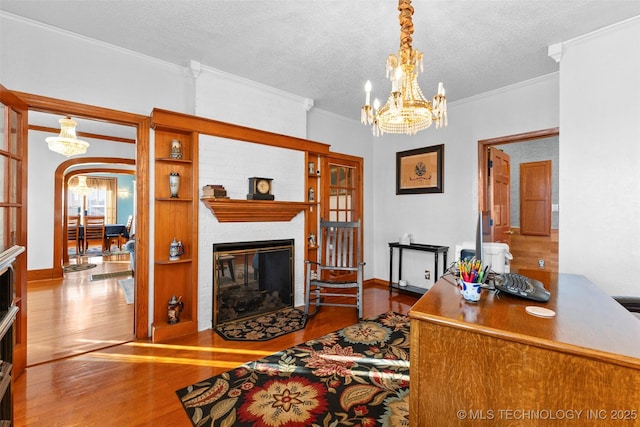 722 E 18th St, Ada, OK 74820 - living area with a fireplace, wood finished floors, a chandelier, ornamental molding, and a textured ceiling