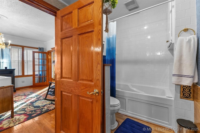 722 E 18th St, Ada, OK 74820 - bathroom featuring wood finished floors, a textured ceiling, shower / tub combo, toilet, and a chandelier