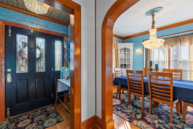 722 E 18th St, Ada, OK 74820 - foyer featuring a chandelier, crown molding, arched walkways, wood finished floors, and a textured ceiling