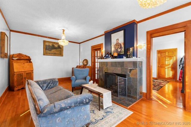 722 E 18th St, Ada, OK 74820 - living area featuring wood finished floors, crown molding, baseboards, a fireplace, and a chandelier