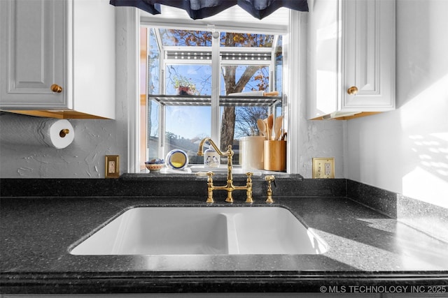 722 E 18th St, Ada, OK 74820 - kitchen view of a sink, dark stone counters, and white cabinetry