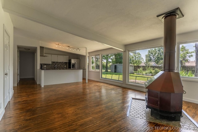 5726 E 26th St, Tulsa, OK 74114 - unfurnished living room featuring a wood stove, dark wood finished floors, baseboards, and a textured ceiling