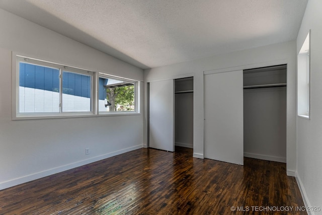 5726 E 26th St, Tulsa, OK 74114 - unfurnished bedroom featuring two closets, dark wood-style floors, a textured ceiling, and baseboards