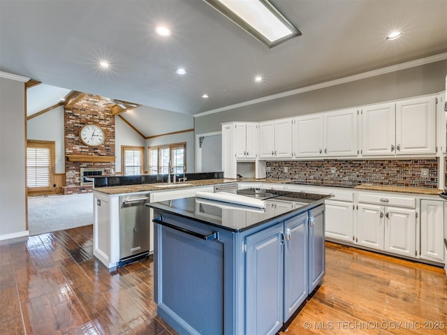 23240 E 90th St S, Broken Arrow, OK 74014 - kitchen featuring blue cabinets, plenty of natural light, a kitchen island, a brick fireplace, and crown molding