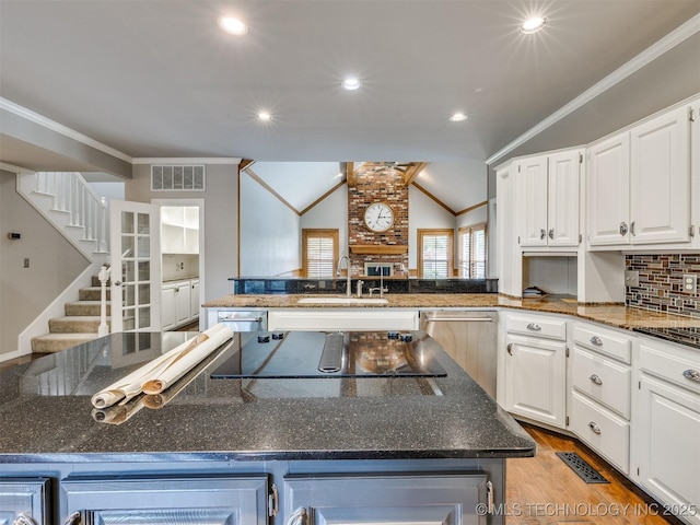 23240 E 90th St S, Broken Arrow, OK 74014 - kitchen with a sink, black electric stovetop, white cabinets, dark stone countertops, and vaulted ceiling