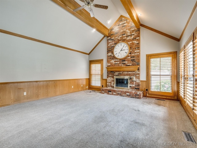 23240 E 90th St S, Broken Arrow, OK 74014 - unfurnished living room featuring a wainscoted wall, beamed ceiling, a ceiling fan, carpet, and a fireplace