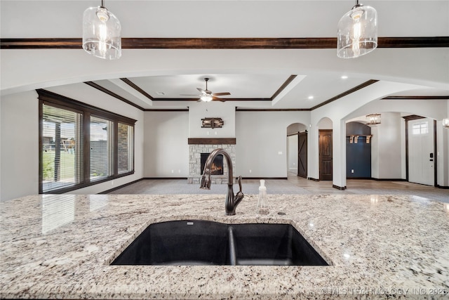 9015 N 65th E Pl, Owasso, OK 74055 - kitchen with a sink, arched walkways, a tray ceiling, light stone counters, and ornamental molding