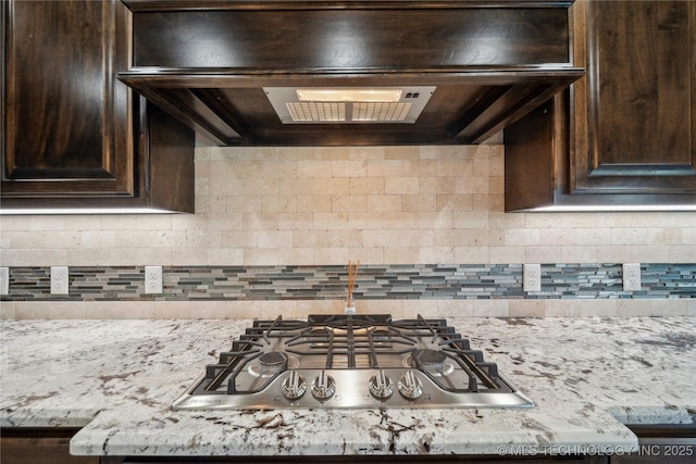 9015 N 65th E Pl, Owasso, OK 74055 - kitchen with stainless steel gas cooktop, dark brown cabinetry, exhaust hood, and backsplash