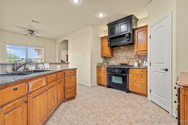 4180 Countyline, Ardmore, OK 73401 - kitchen featuring a sink, backsplash, black range with gas stovetop, ceiling fan, and arched walkways