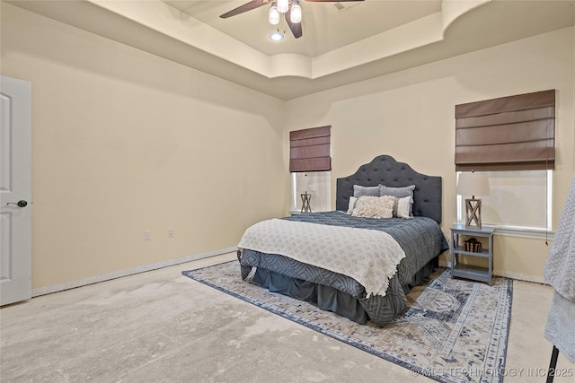 4180 Countyline, Ardmore, OK 73401 - bedroom featuring unfinished concrete flooring, a tray ceiling, ceiling fan, and baseboards