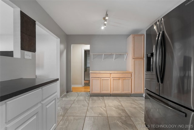 1228 S Erie Ave, Tulsa, OK 74112 - kitchen with stainless steel refrigerator with ice dispenser, open shelves, light marble finish floors, dark countertops, and baseboards