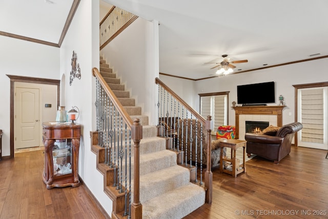 316 E 44th St, Sand Springs, OK 74063 - stairway with crown molding, ceiling fan, wood-type flooring, and a tile fireplace