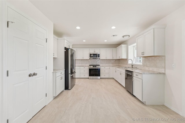2817 W Oakland St, Broken Arrow, OK 74012 - kitchen featuring appliances with stainless steel finishes, a sink, tasteful backsplash, light stone countertops, and white cabinetry