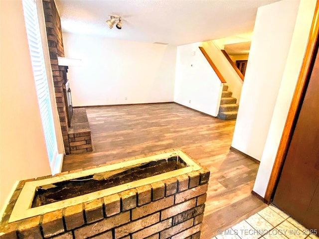 7205 S Date Pl, Broken Arrow, OK 74011 - unfurnished living room with stairs, wood finished floors, baseboards, and a brick fireplace