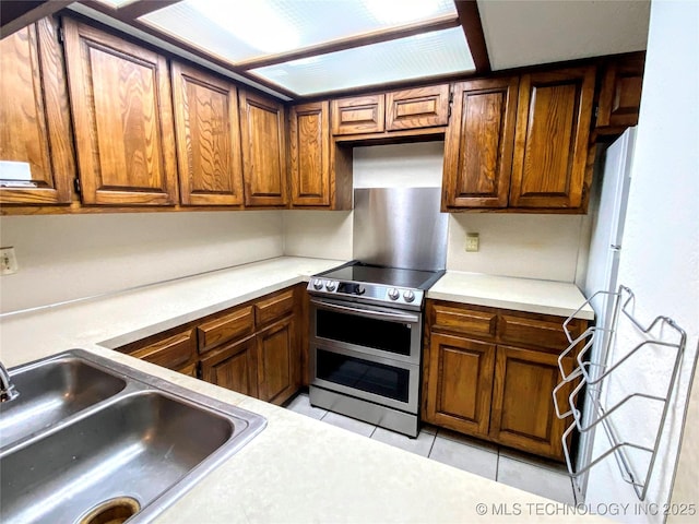 7205 S Date Pl, Broken Arrow, OK 74011 - kitchen featuring range with two ovens, a sink, light tile patterned floors, light countertops, and brown cabinetry