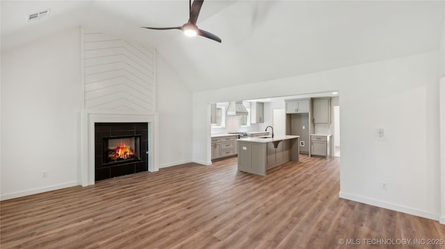 2508 W Birmingham St, Broken Arrow, OK 74011 - unfurnished living room with high vaulted ceiling, a ceiling fan, light wood finished floors, and a fireplace