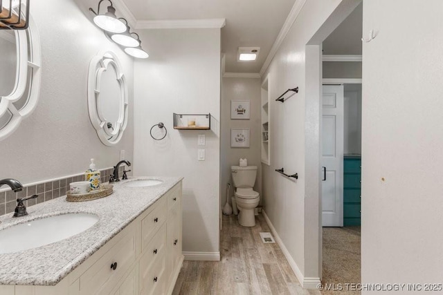 412 W Los Angeles St, Broken Arrow, OK 74011 - bathroom with wood finished floors, double vanity, ornamental molding, toilet, and baseboards