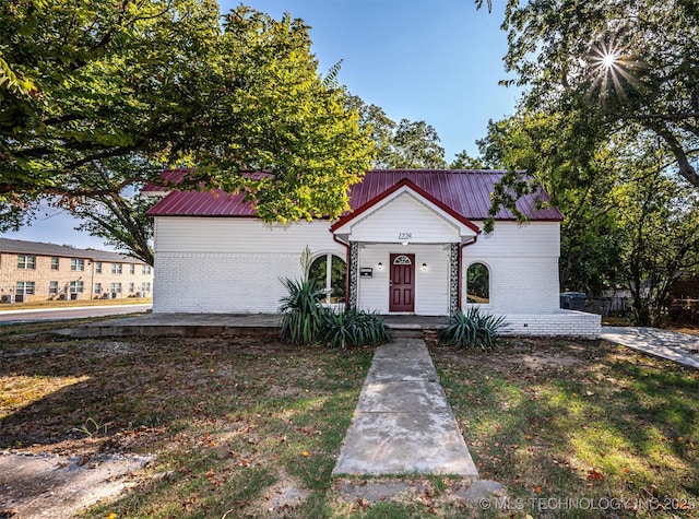 1228 D St NW, Ardmore, OK 73401 - view of front of property with brick siding, metal roof, and a front lawn
