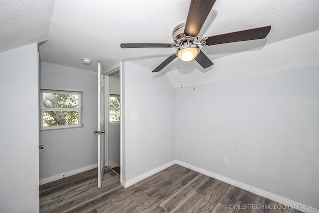 1228 D St NW, Ardmore, OK 73401 - unfurnished bedroom featuring dark wood-style floors, a textured ceiling, baseboards, ceiling fan, and lofted ceiling