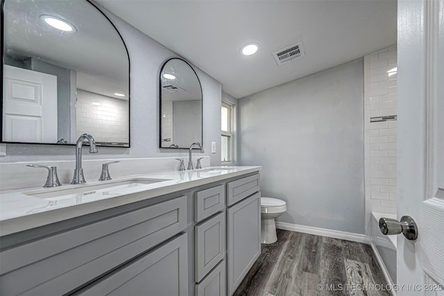 1228 D St NW, Ardmore, OK 73401 - bathroom with double vanity, wood finished floors, toilet, baseboards, and recessed lighting
