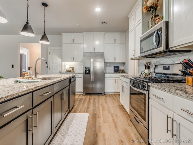 7221 S Indianwood Ave, Broken Arrow, OK 74011 - kitchen with appliances with stainless steel finishes, a sink, light wood finished floors, tasteful backsplash, and white cabinets