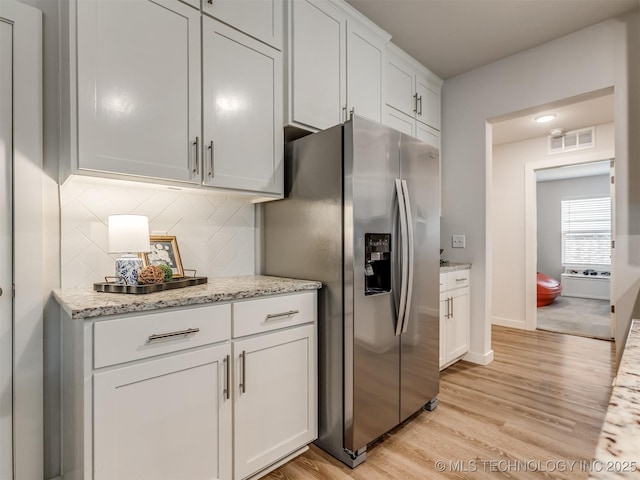 7221 S Indianwood Ave, Broken Arrow, OK 74011 - kitchen with stainless steel fridge with ice dispenser, light wood-style floors, decorative backsplash, white cabinets, and light stone countertops