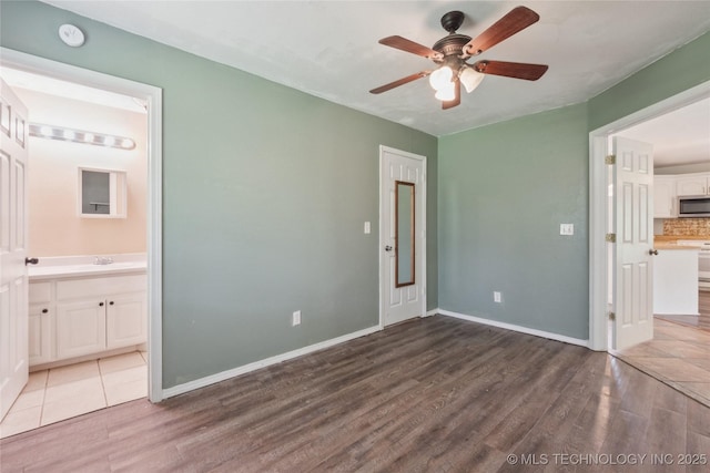 385077 E 1160th Rd, Weleetka, OK 74880 - unfurnished bedroom with wood finished floors, baseboards, a sink, and ensuite bathroom