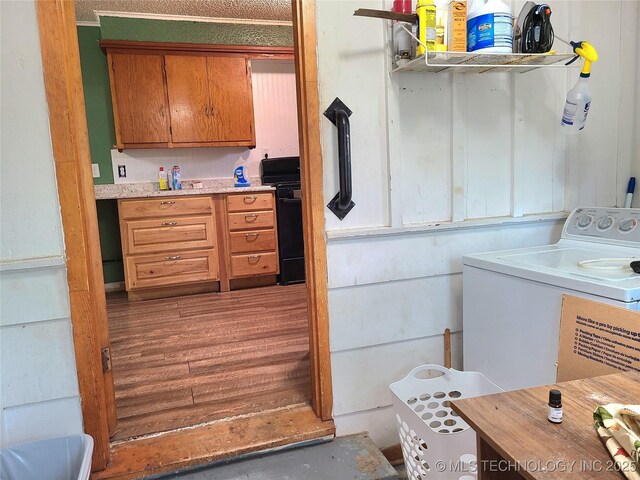 1950 Cedar Bluff Rd, Fort Gibson, OK 74434 - kitchen with washer / dryer, black range oven, brown cabinetry, light countertops, and wood finished floors