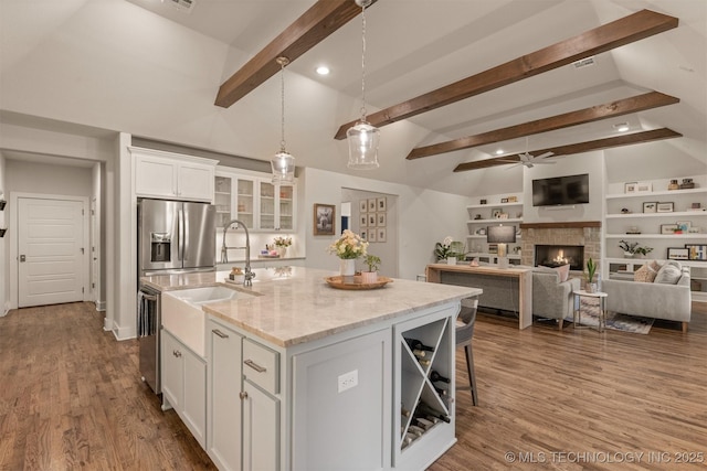 6705 S Palm Ave, Broken Arrow, OK 74011 - kitchen featuring appliances with stainless steel finishes, a ceiling fan, white cabinets, an island with sink, and a stone fireplace