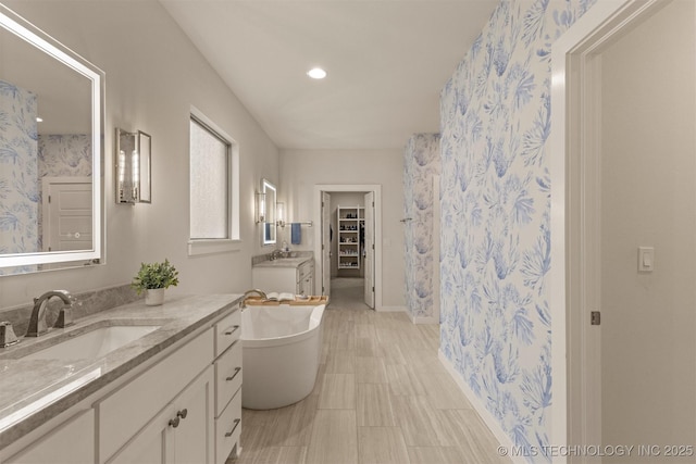 6705 S Palm Ave, Broken Arrow, OK 74011 - bathroom with two vanities, a freestanding bath, baseboards, wallpapered walls, and recessed lighting