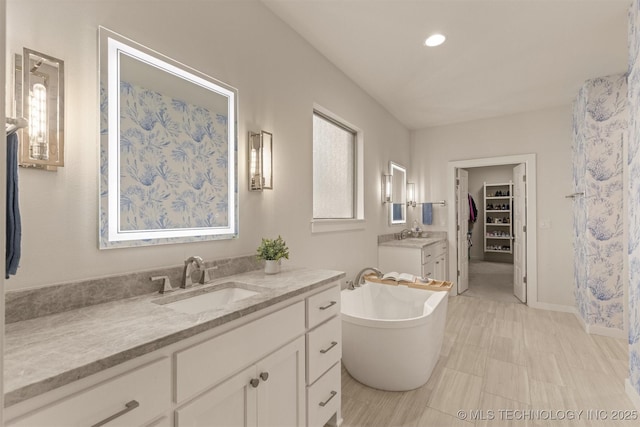 6705 S Palm Ave, Broken Arrow, OK 74011 - bathroom featuring vanity, a freestanding tub, a spacious closet, and baseboards