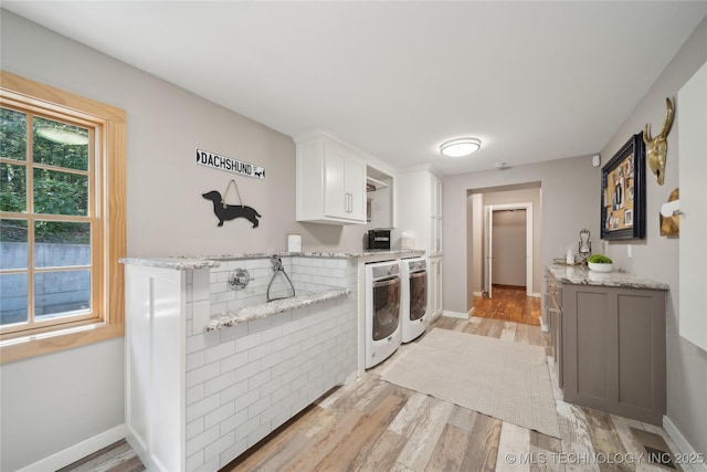 20119 E Willis Rd, Tahlequah, OK 74464 - kitchen featuring washer and dryer, light wood-style floors, white cabinets, light stone countertops, and baseboards