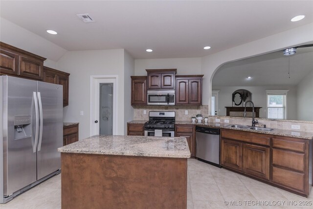 9241 N 144th E Ave, Owasso, OK 74055 - kitchen with stainless steel appliances, a sink, tasteful backsplash, light stone countertops, and arched walkways