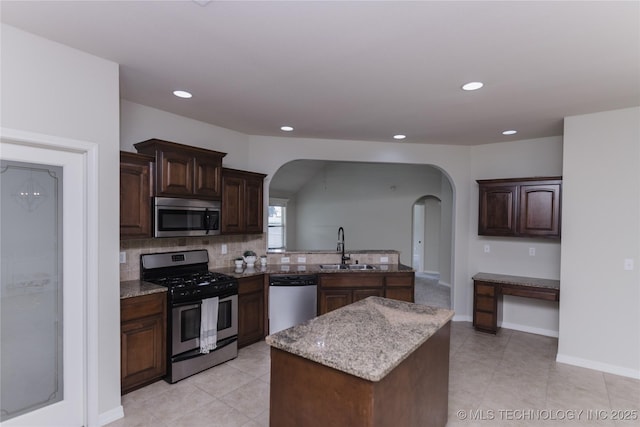 9241 N 144th E Ave, Owasso, OK 74055 - kitchen with stainless steel appliances, arched walkways, a sink, backsplash, and light stone countertops
