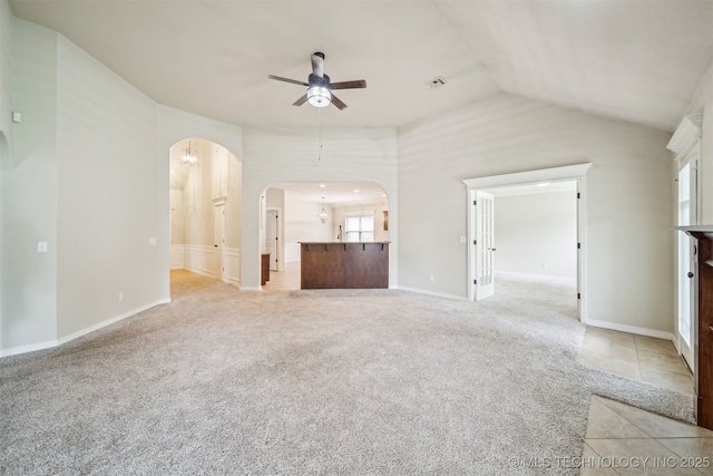 9241 N 144th E Ave, Owasso, OK 74055 - unfurnished living room featuring arched walkways, a ceiling fan, light colored carpet, vaulted ceiling, and baseboards