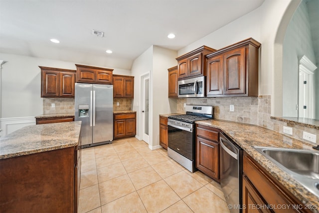 9241 N 144th E Ave, Owasso, OK 74055 - kitchen with appliances with stainless steel finishes, arched walkways, backsplash, light tile patterned flooring, and light stone counters
